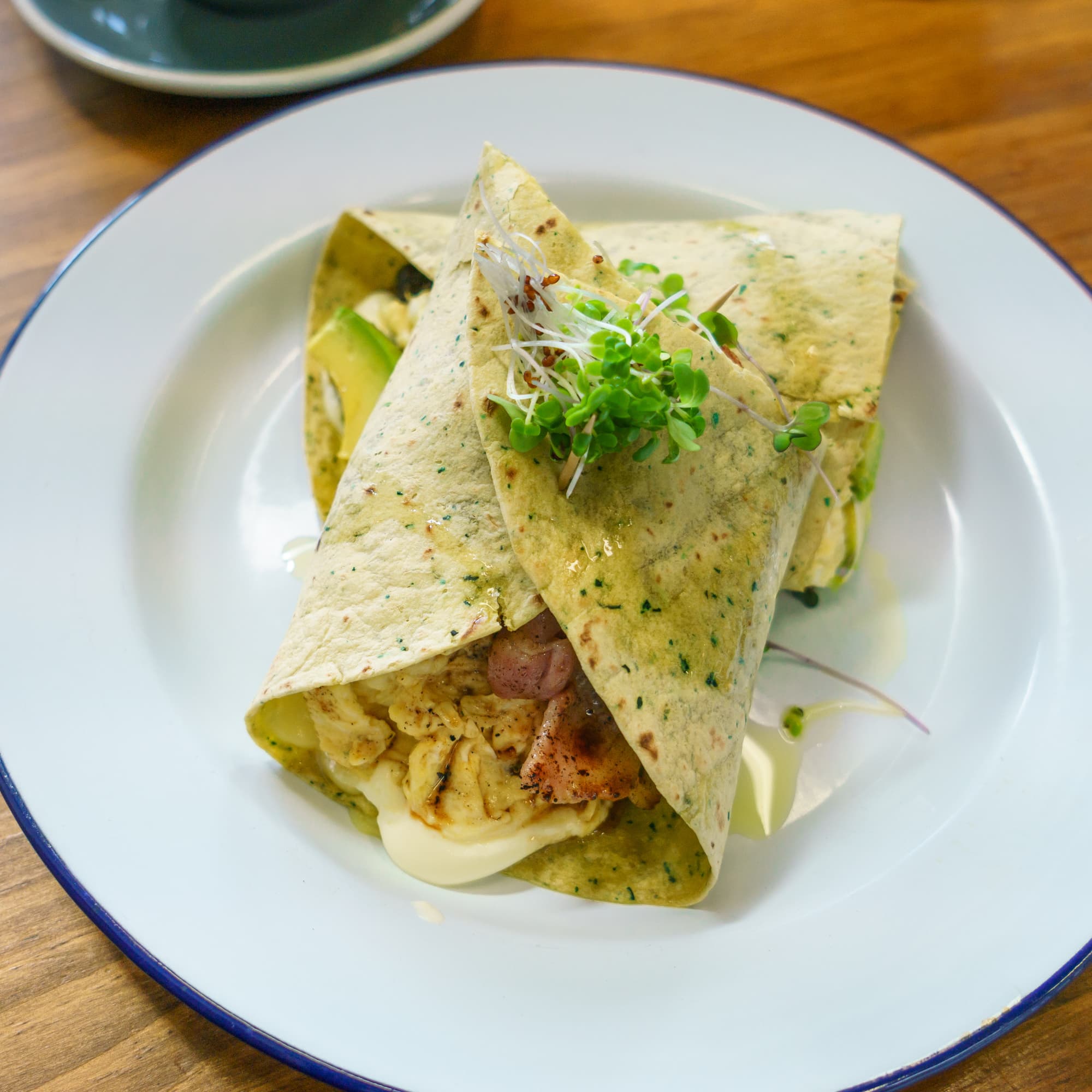 Breakfast burrito — Scrambled eggs, bacon, guacamole, chipotle, sour cream and spciy mexican beans in a spinach wrap.